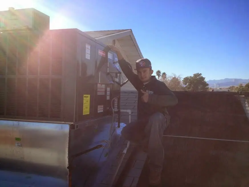 HVAC technician performing AC Tune-Up on a rooftop unit in Beach Park